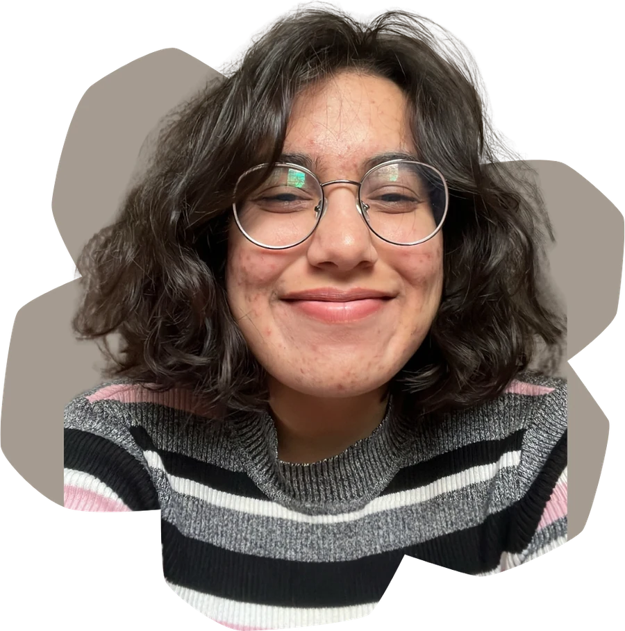 Ria smiling, in round glasses and a striped sweater
